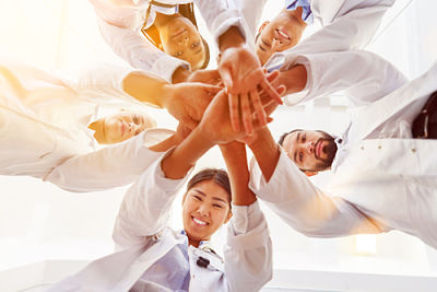 Picture of a group of hospital employees staking their hands on top of each other as a community.